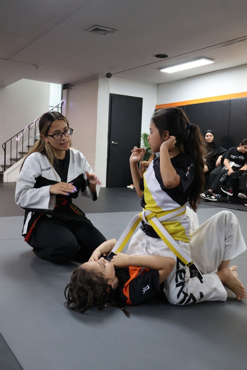 Female instructor coaching a seated girl at ZENTAI Martial Arts in North Arlington, NJ