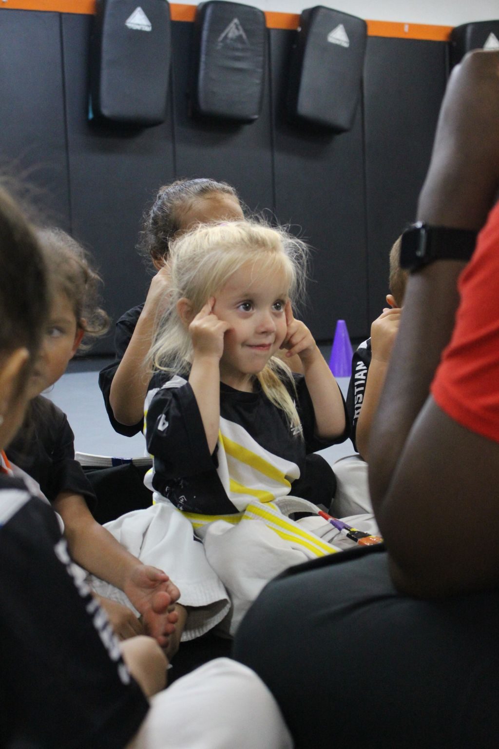 Little girl covering her ears and smiling at ZENTAI Martial Arts in North Arlington, NJ
