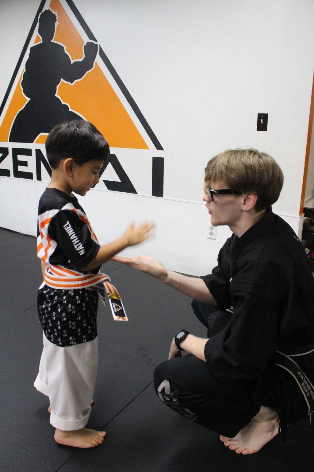 Teen instructor high-fiving a little boy at ZENTAI Martial Arts in North Arlington, NJ