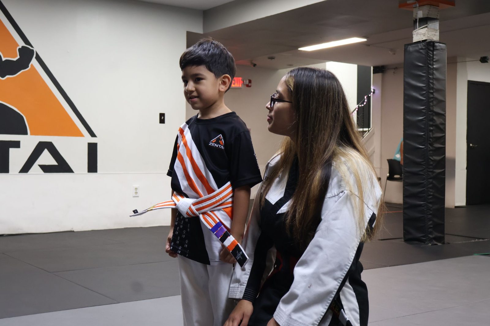Female black belt instructor talking with a boy at eye level at ZENTAI Martial Arts in North Arlington, NJ