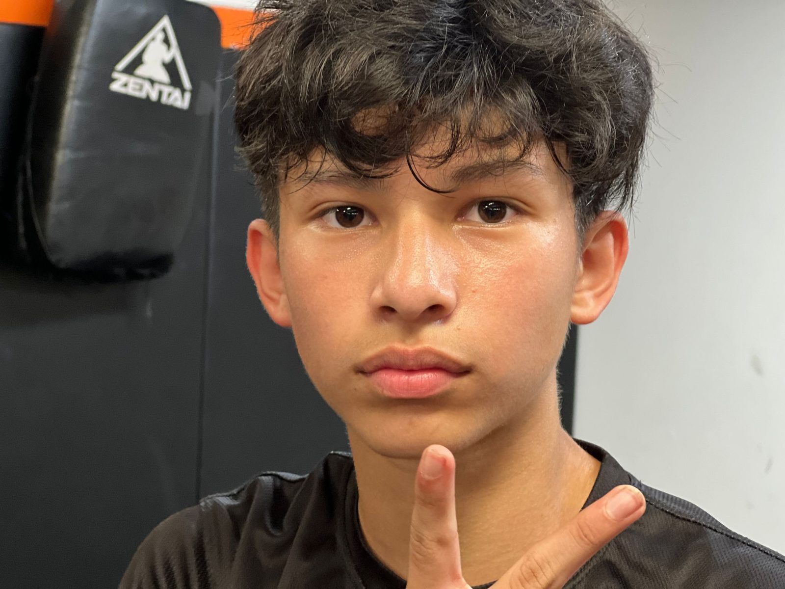 Smiling teen in front of the ZENTAI logo at ZENTAI Martial Arts in New Jersey