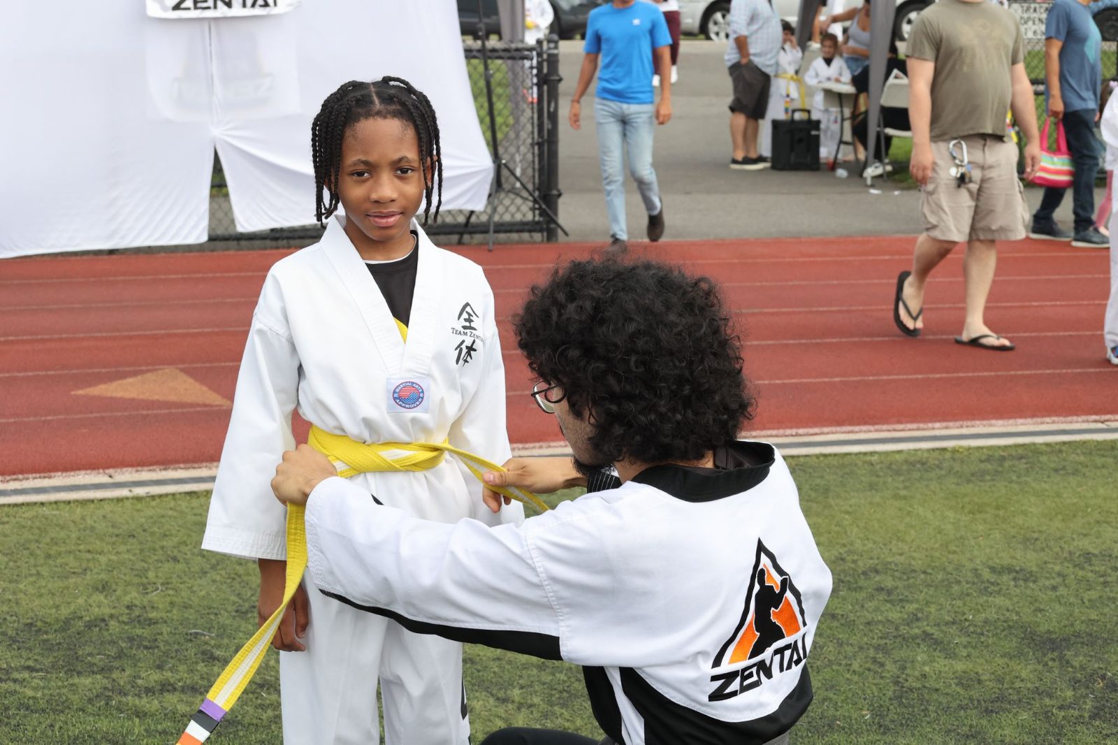 Instructor tying a new belt on a young girl at a ZENTAI Martial Arts belt promotion in New Jersey