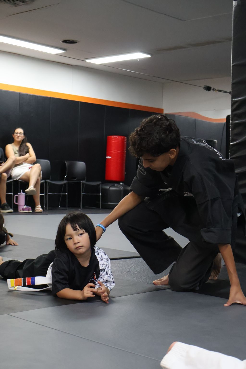 Instructor kneeling to help a small girl at ZENTAI Martial Arts in North Arlington, NJ
