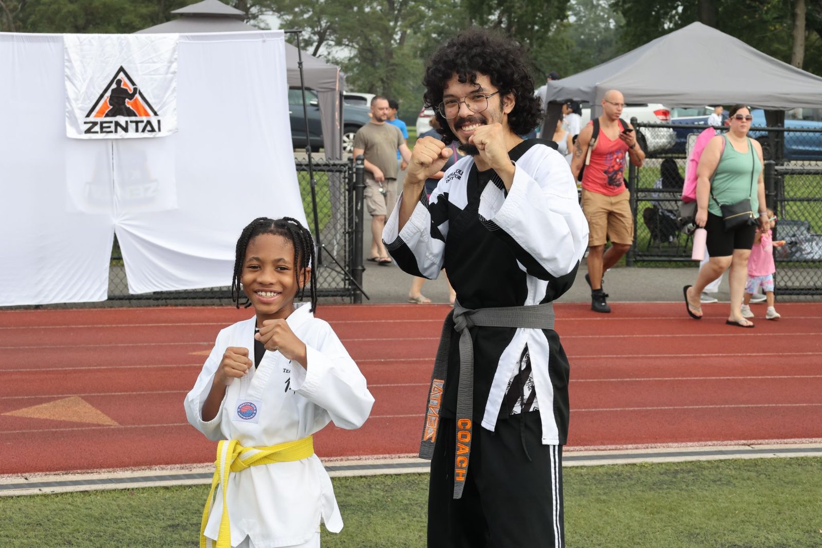 Young girl smiling with a black belt instructor at the ZENTAI Mega Belt Promotion in New Jersey