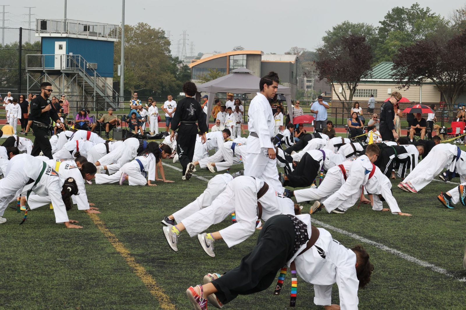 A group of students doing push-ups on the field at the ZENTAI Mega Belt Promotion in New Jersey