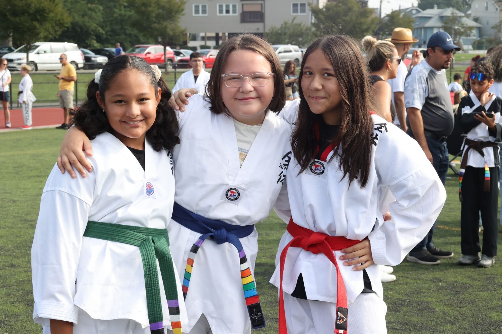 Three girls smiling with their belts at the ZENTAI Mega Belt Promotion in New Jersey