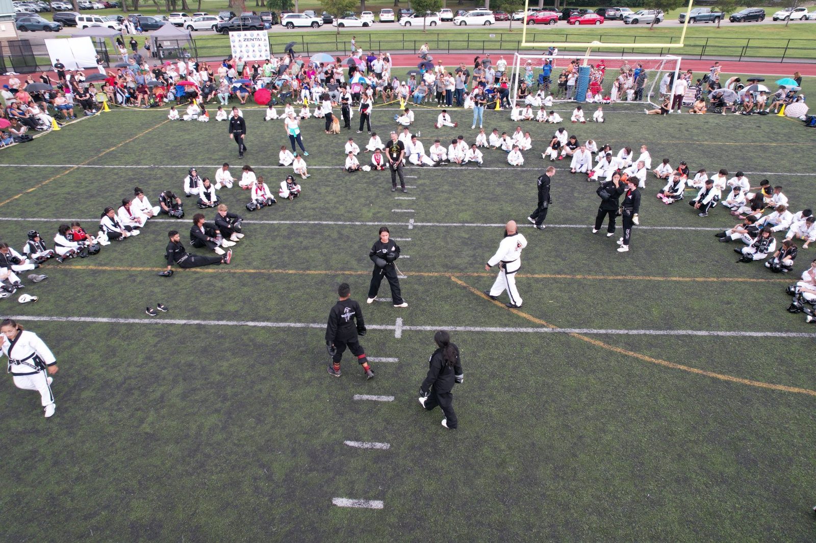 Students gathered in a large circle on the field at the ZENTAI Mega Belt Promotion in New Jersey