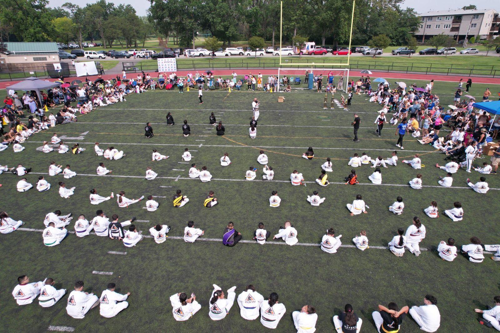 A large group in white uniforms on the field at the ZENTAI Mega Belt Promotion in New Jersey
