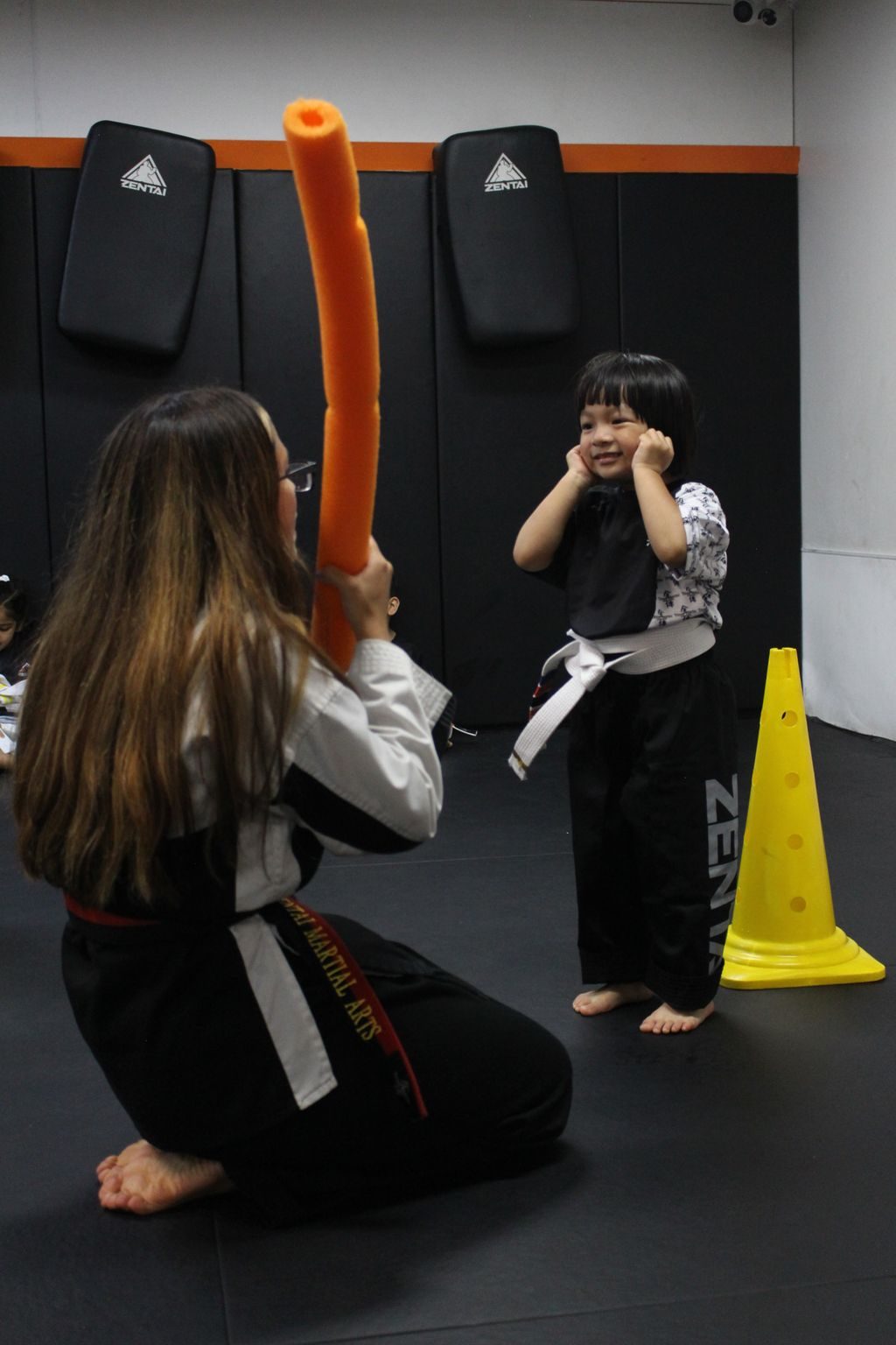 Instructor playing a foam noodle game with a young girl at ZENTAI Martial Arts in North Arlington, NJ