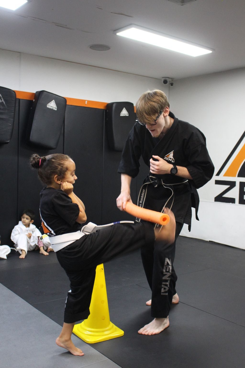 Young boy kicking a target with an instructor at ZENTAI Martial Arts in North Arlington, NJ