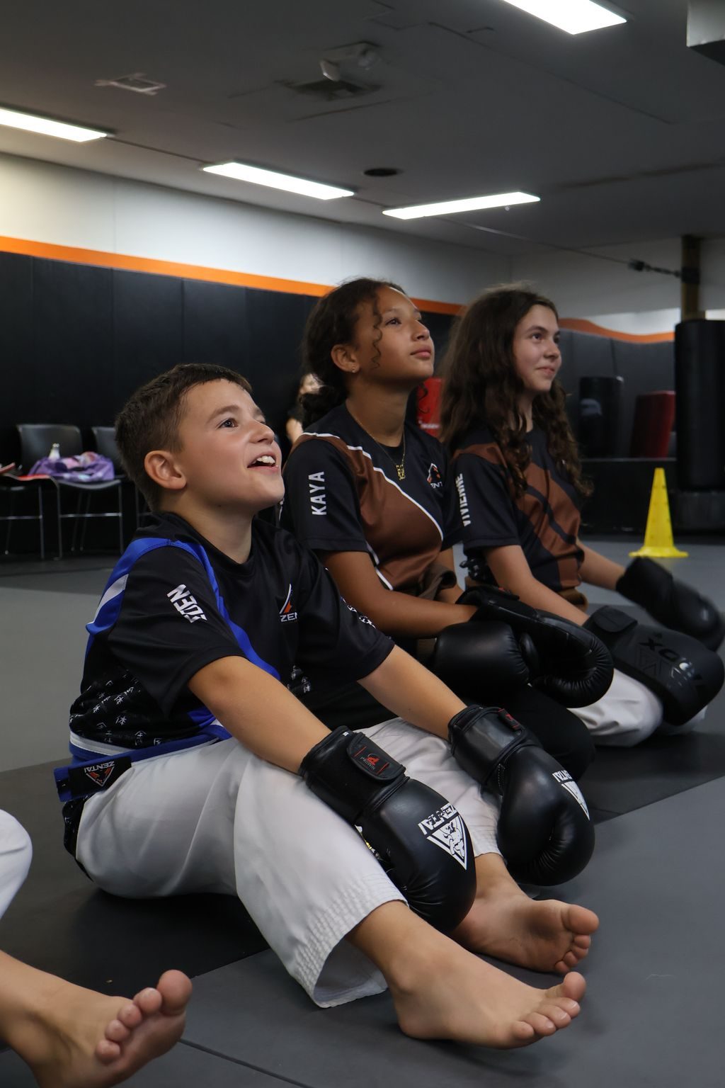 Boys laughing while sitting with their gloves at ZENTAI Martial Arts in North Arlington, NJ